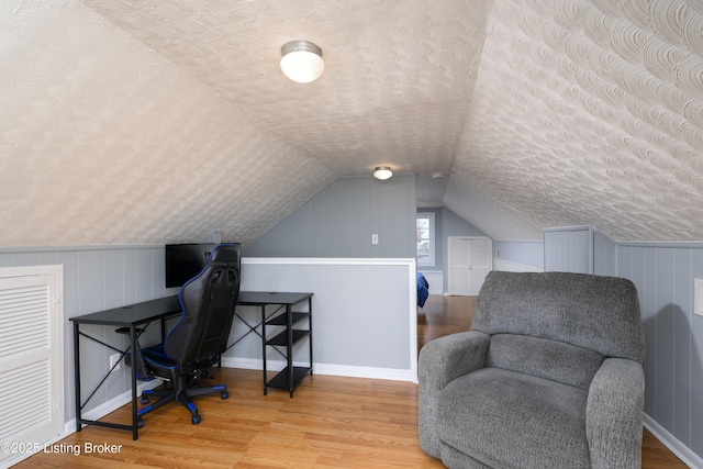 office space with lofted ceiling, hardwood / wood-style floors, and a textured ceiling