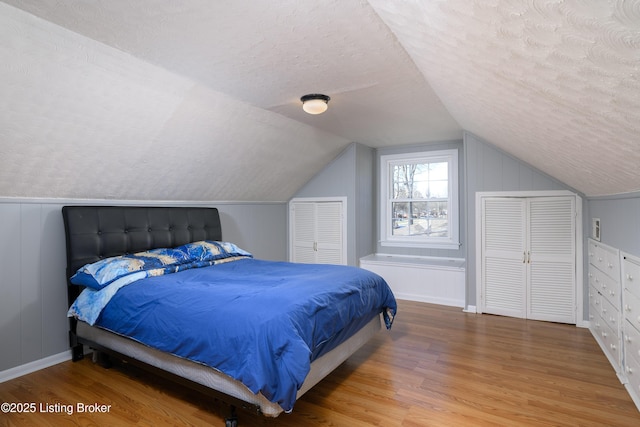 bedroom with lofted ceiling, hardwood / wood-style floors, and a textured ceiling