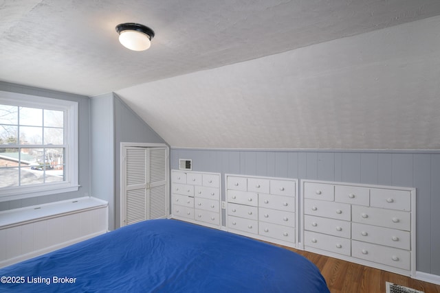 unfurnished bedroom with wood-type flooring, lofted ceiling, a textured ceiling, and a closet