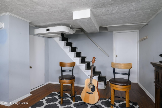 stairs with ornamental molding, hardwood / wood-style floors, and a textured ceiling