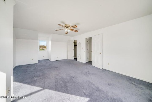 empty room with ceiling fan and dark colored carpet