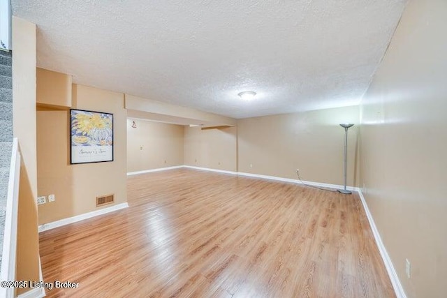 unfurnished room with light hardwood / wood-style flooring and a textured ceiling