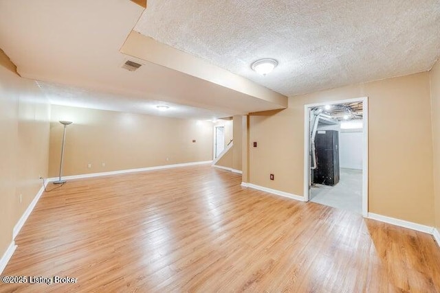 basement with light hardwood / wood-style flooring and a textured ceiling