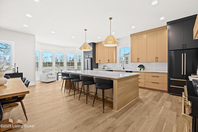 kitchen featuring a center island, light brown cabinets, light hardwood / wood-style floors, and decorative light fixtures