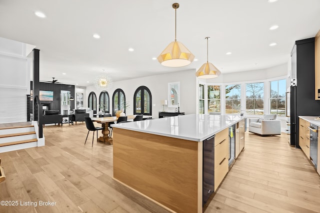 kitchen with wine cooler, light wood-type flooring, high end black fridge, pendant lighting, and a large island