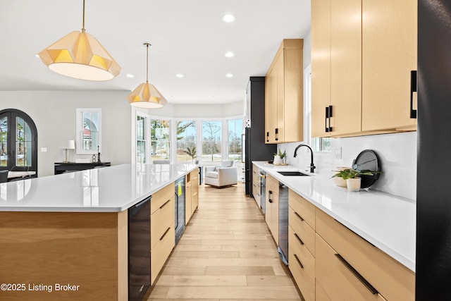 kitchen with pendant lighting, light brown cabinetry, sink, a large island, and a healthy amount of sunlight