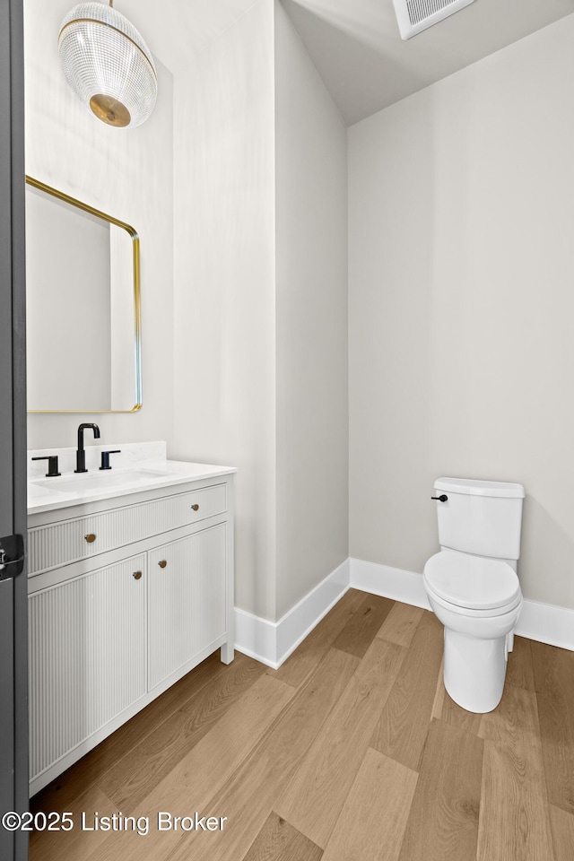 bathroom featuring wood-type flooring, toilet, and vanity