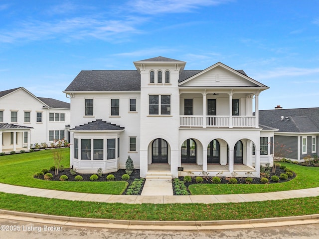 view of front facade featuring a front yard, a balcony, and covered porch