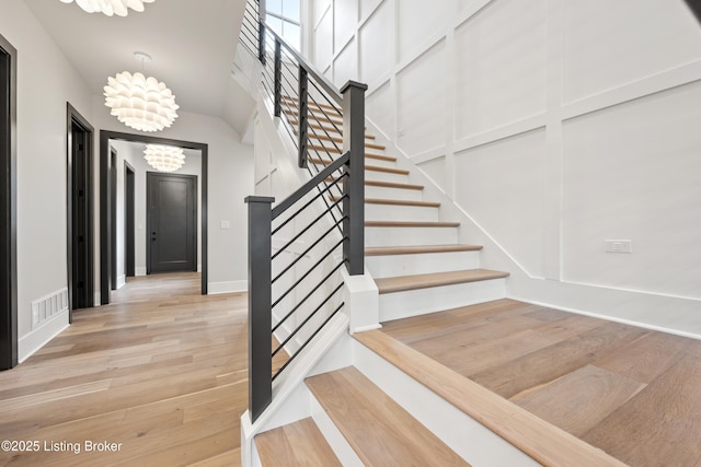 staircase featuring hardwood / wood-style floors and a notable chandelier