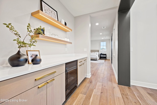 bar featuring wine cooler, light brown cabinetry, and light hardwood / wood-style floors