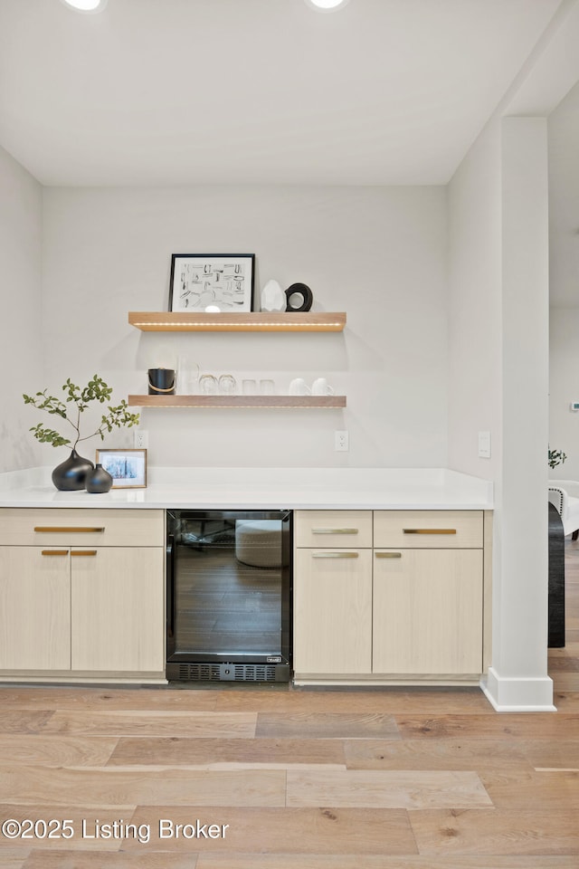 bar with wine cooler and light hardwood / wood-style flooring