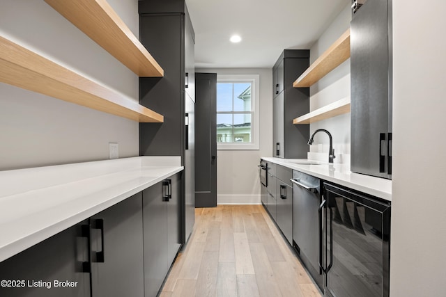 kitchen with sink, beverage cooler, and light wood-type flooring