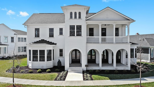 view of front facade featuring roof with shingles, french doors, a balcony, a front yard, and a porch