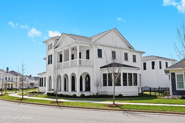 view of front of property with a balcony, a front yard, stucco siding, and fence