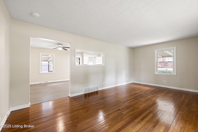 spare room featuring ceiling fan, a healthy amount of sunlight, dark hardwood / wood-style floors, and a textured ceiling