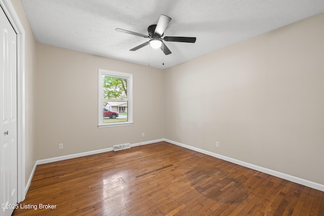 unfurnished room with ceiling fan, a textured ceiling, and dark hardwood / wood-style flooring