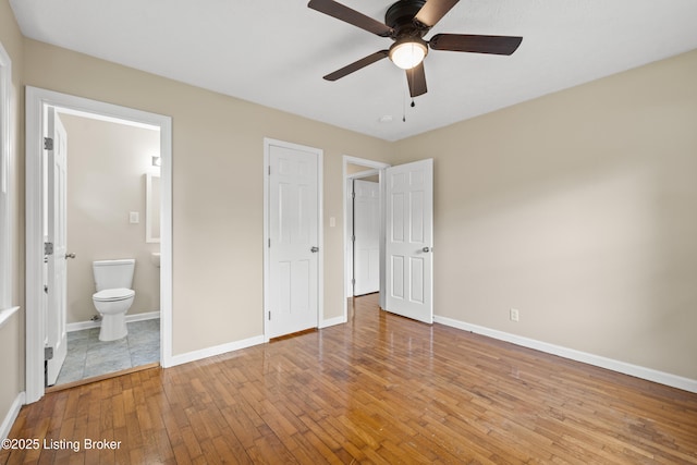 unfurnished bedroom featuring ceiling fan, ensuite bathroom, and light hardwood / wood-style floors