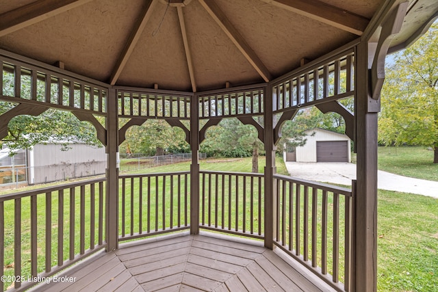 wooden terrace with a garage, a gazebo, a yard, and an outbuilding