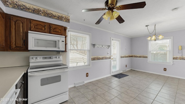 kitchen with light tile patterned flooring, dark brown cabinets, hanging light fixtures, ornamental molding, and white appliances