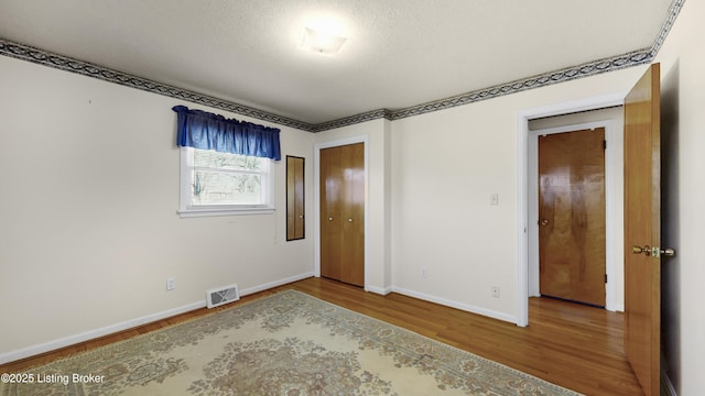 unfurnished bedroom with hardwood / wood-style flooring, a textured ceiling, and a closet