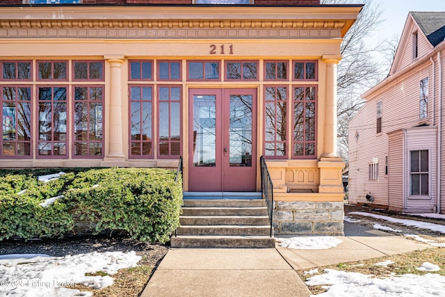 snow covered property entrance with french doors