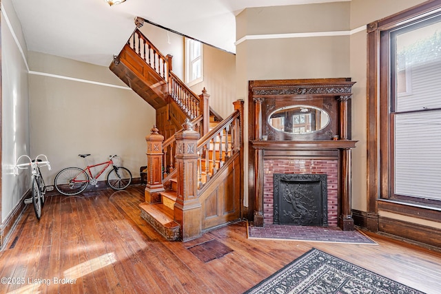 stairway with hardwood / wood-style flooring and a brick fireplace