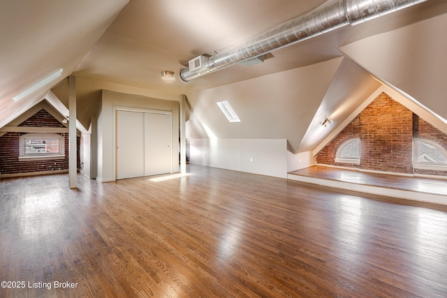 additional living space featuring lofted ceiling, brick wall, and hardwood / wood-style floors