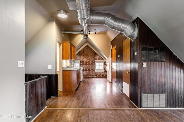 additional living space with brick wall, dark hardwood / wood-style flooring, and wood walls