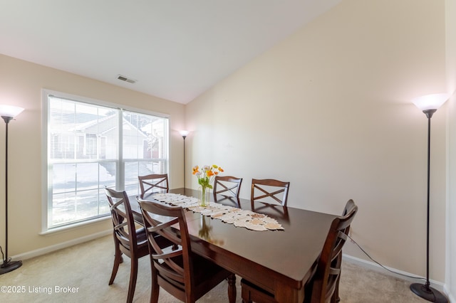 dining room featuring vaulted ceiling and light colored carpet