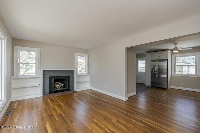 unfurnished living room with a brick fireplace, a wealth of natural light, and built in features