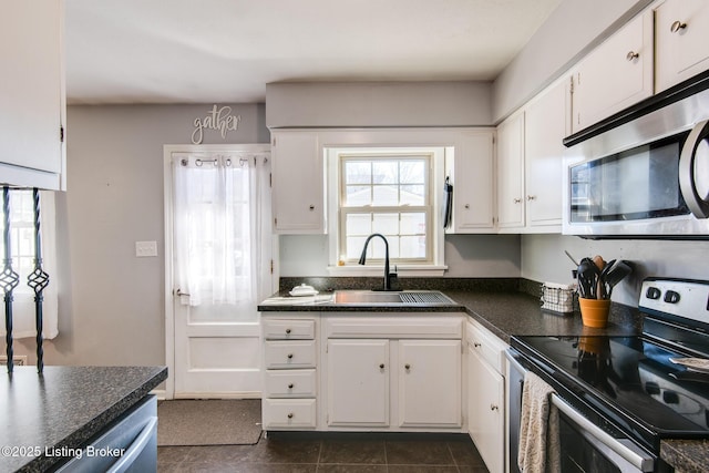 kitchen featuring sink, dark tile patterned flooring, white cabinets, and appliances with stainless steel finishes