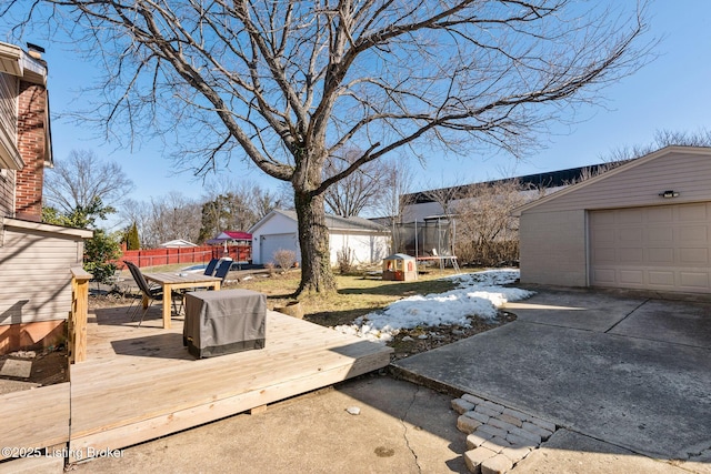 deck featuring a garage, an outbuilding, and a trampoline