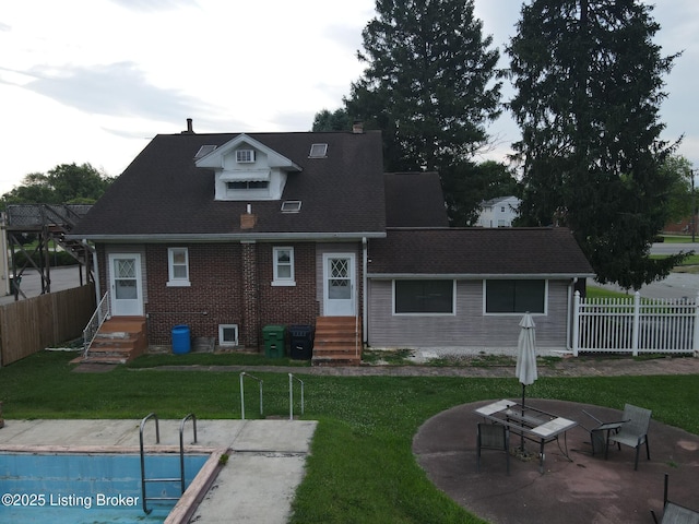 rear view of house with a covered pool, a patio, and a lawn