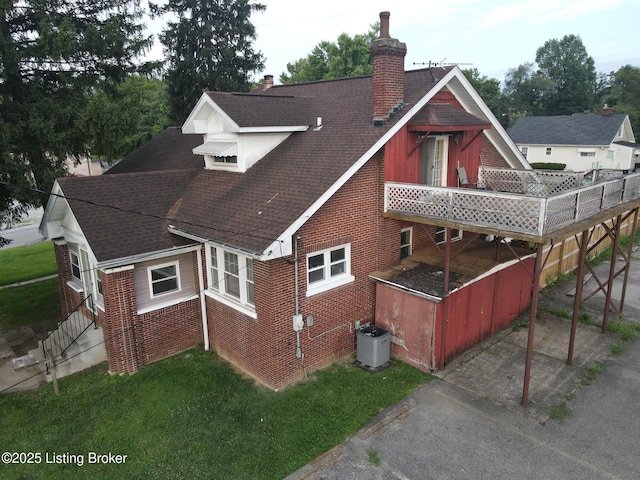 back of house with central AC, a wooden deck, and a lawn