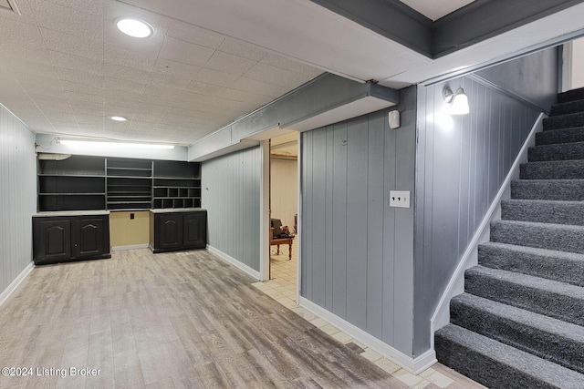 basement featuring hardwood / wood-style flooring and wooden walls