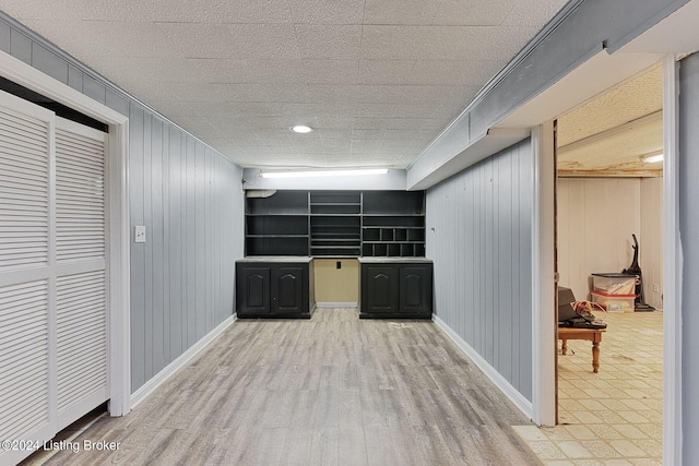 basement with light hardwood / wood-style flooring and wooden walls