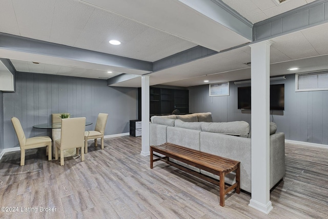 living room featuring ornate columns, hardwood / wood-style floors, and wood walls