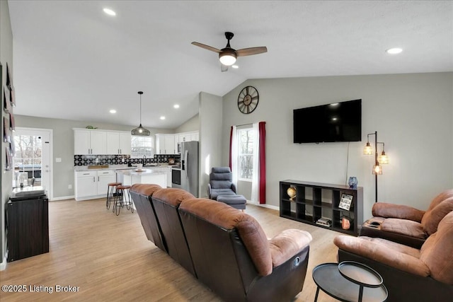 living room featuring vaulted ceiling, a healthy amount of sunlight, and light hardwood / wood-style flooring