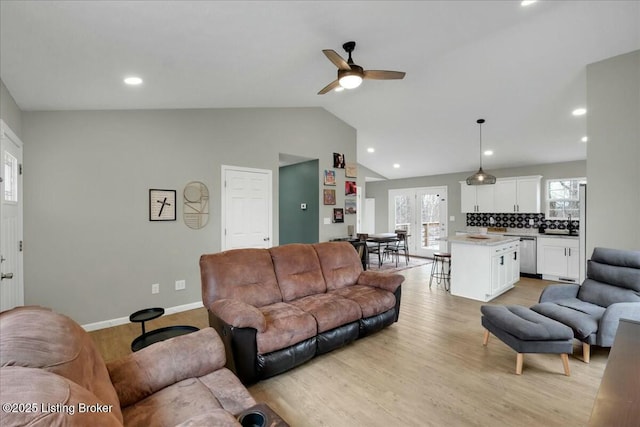 living room with ceiling fan, lofted ceiling, and light hardwood / wood-style floors