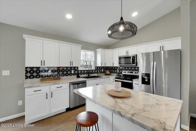 kitchen with sink, white cabinets, hanging light fixtures, stainless steel appliances, and light stone countertops