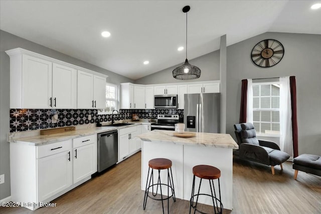 kitchen featuring stainless steel appliances, white cabinetry, a kitchen island, and decorative light fixtures