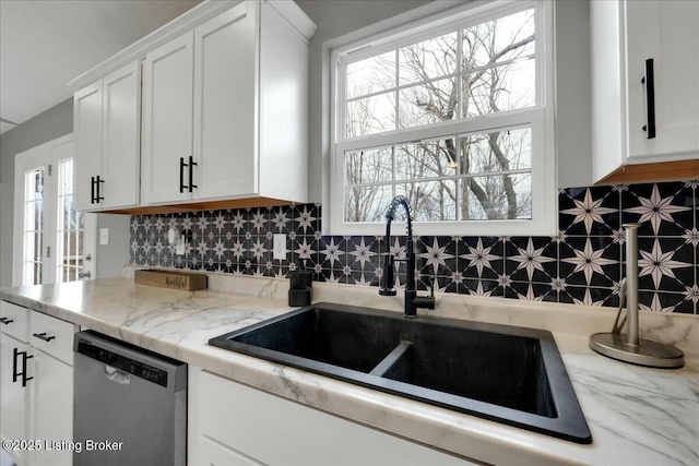 kitchen featuring sink, stainless steel dishwasher, white cabinets, and backsplash