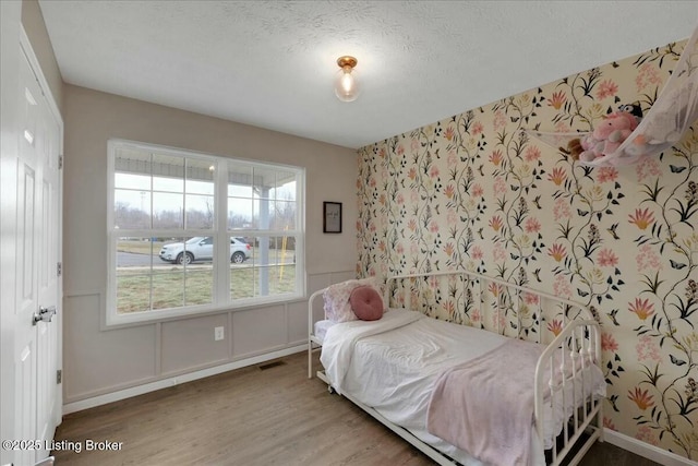 bedroom with multiple windows, wood-type flooring, and a textured ceiling