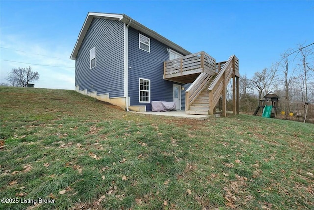 back of property featuring a wooden deck, a yard, a patio area, and a playground