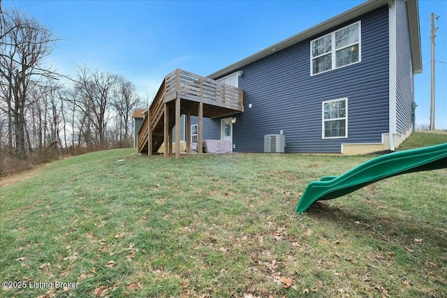 back of house featuring a yard, central AC, and a playground