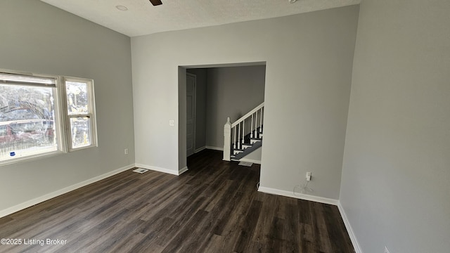 spare room featuring dark wood-type flooring, ceiling fan, and a textured ceiling