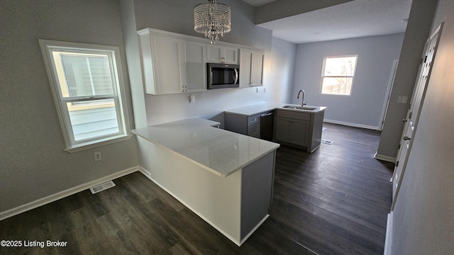 kitchen with sink, white cabinetry, decorative light fixtures, black dishwasher, and kitchen peninsula