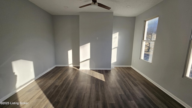 spare room featuring ceiling fan, dark wood-type flooring, and a textured ceiling