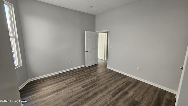 unfurnished room featuring dark hardwood / wood-style flooring and a textured ceiling