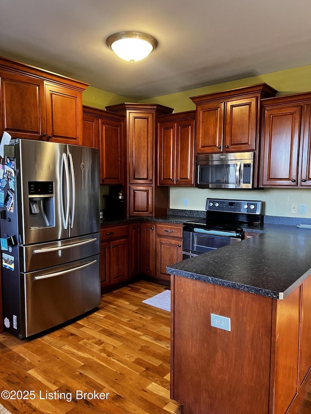 kitchen featuring stainless steel appliances, kitchen peninsula, and light hardwood / wood-style flooring